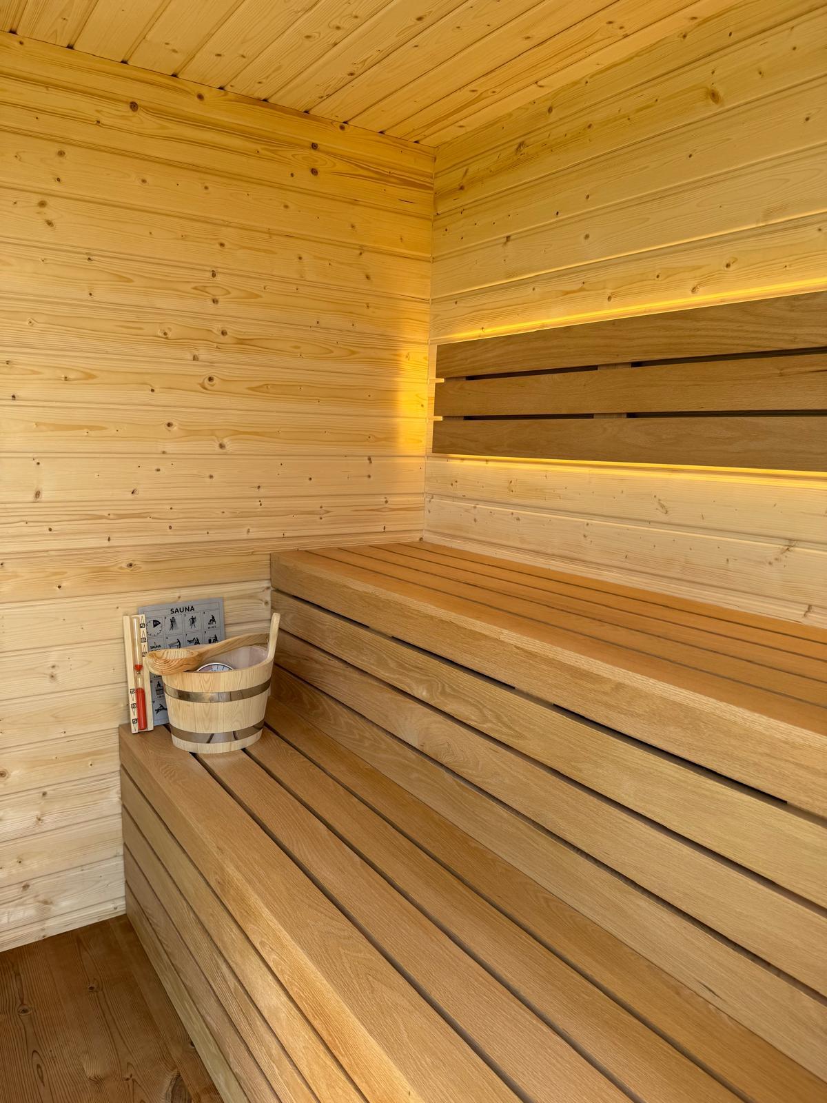 Intérieur d'un sauna finlandais en bois clair avec banquettes éclairées
